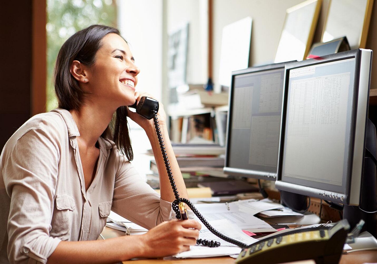 girl talking on phone and working on computer