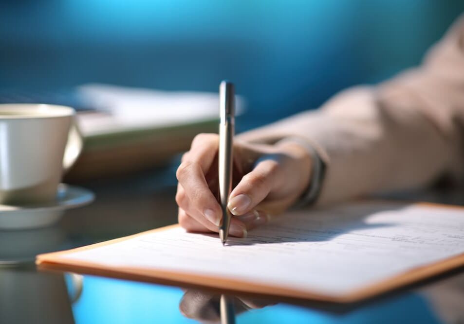 A hand holding a pen filling out a form.