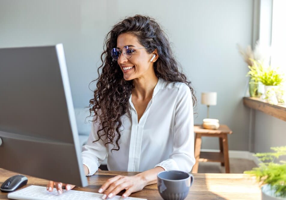 A woman smiling while using desktop computer.